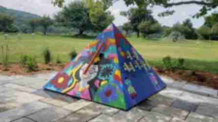 Colorful pyramid amid the Artpark percussion garden in front of a green field surrounded by trees on a semi cloudy day