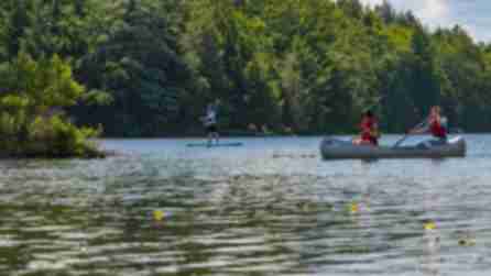 A photo of two people in a canoe and one person paddle boarding on the North-South Lake Campground