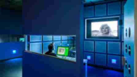 A person sitting at a desk in a blue lit room with a computer
