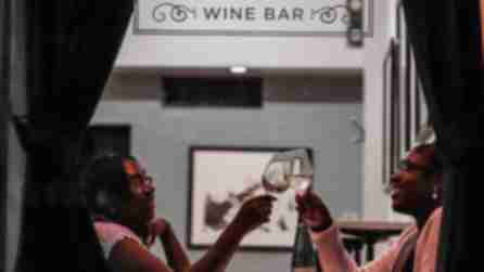 Two women clink glasses at a table inside Apogee Wine Bar in the Finger Lakes