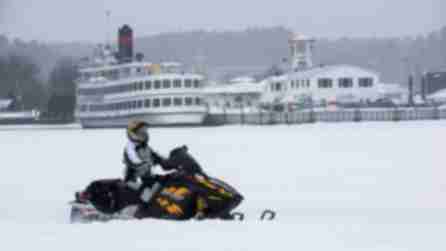 A person on a snowmobile near the boats of the Lake George Steamboat Company during the Lake George Winter Carnival