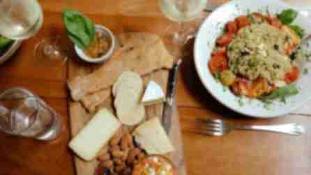 White wine, crackers, cheese, and almonds displayed on a wooden table at Moosewood Restaurant along with a couscous salad