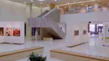 Art hangs on the white walls surrounding a grey central staircase in the gallery of the Dyer Arts Center