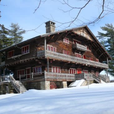 A snow-covered large log cabin surrounded by snowy grounds