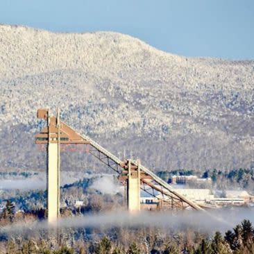 Snow-covered mountains loom behind the Olympic Ski Jumping Complex in Lake Placid